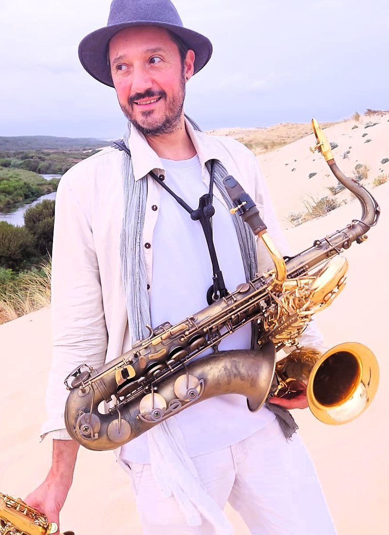 Ash Belgeri, saxophone baryton en bandoulière, dans les dunes