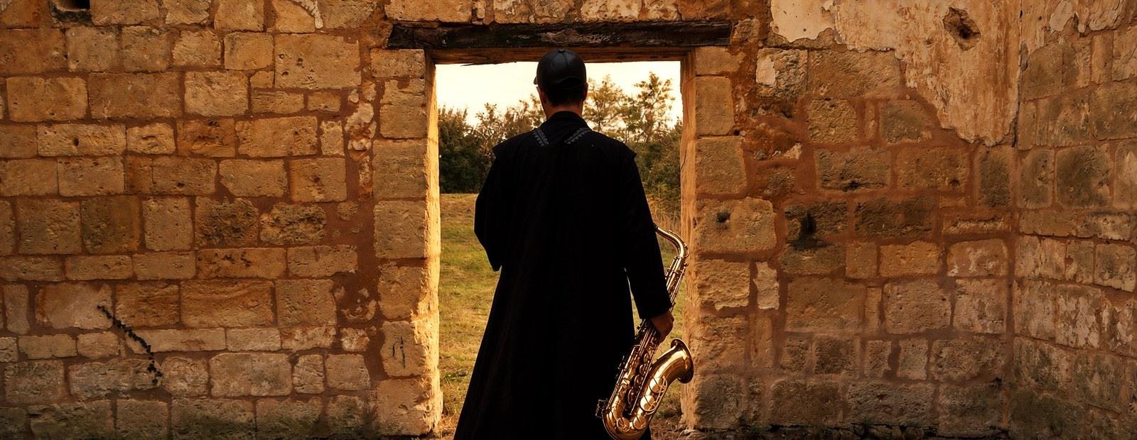 Ash Belgeri de dos dans l'embrasure d'une ruine de pierre, la lumière du soir dehors